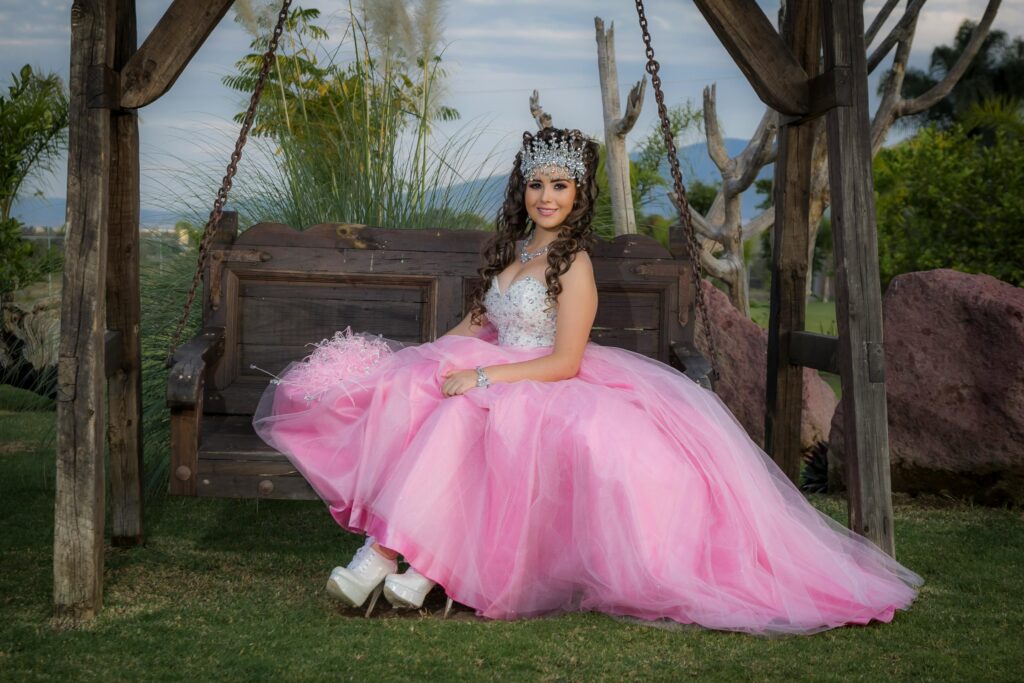 pexels-photo-5795551-5795551 Young girl in glamorous pink tulle dress sitting on a wooden swing outdoors, wearing a tiara.